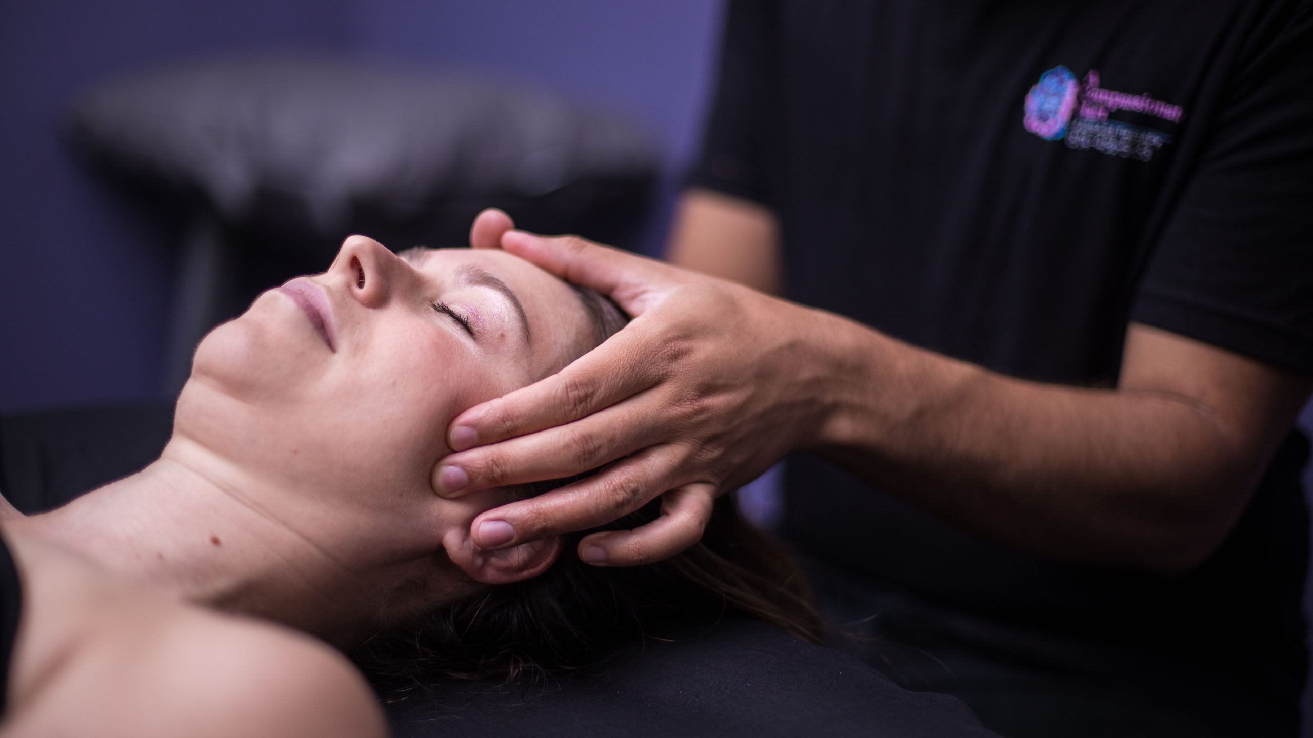 Close-up photo of massage therapist working on the temples and forehead of a client during branding photo session