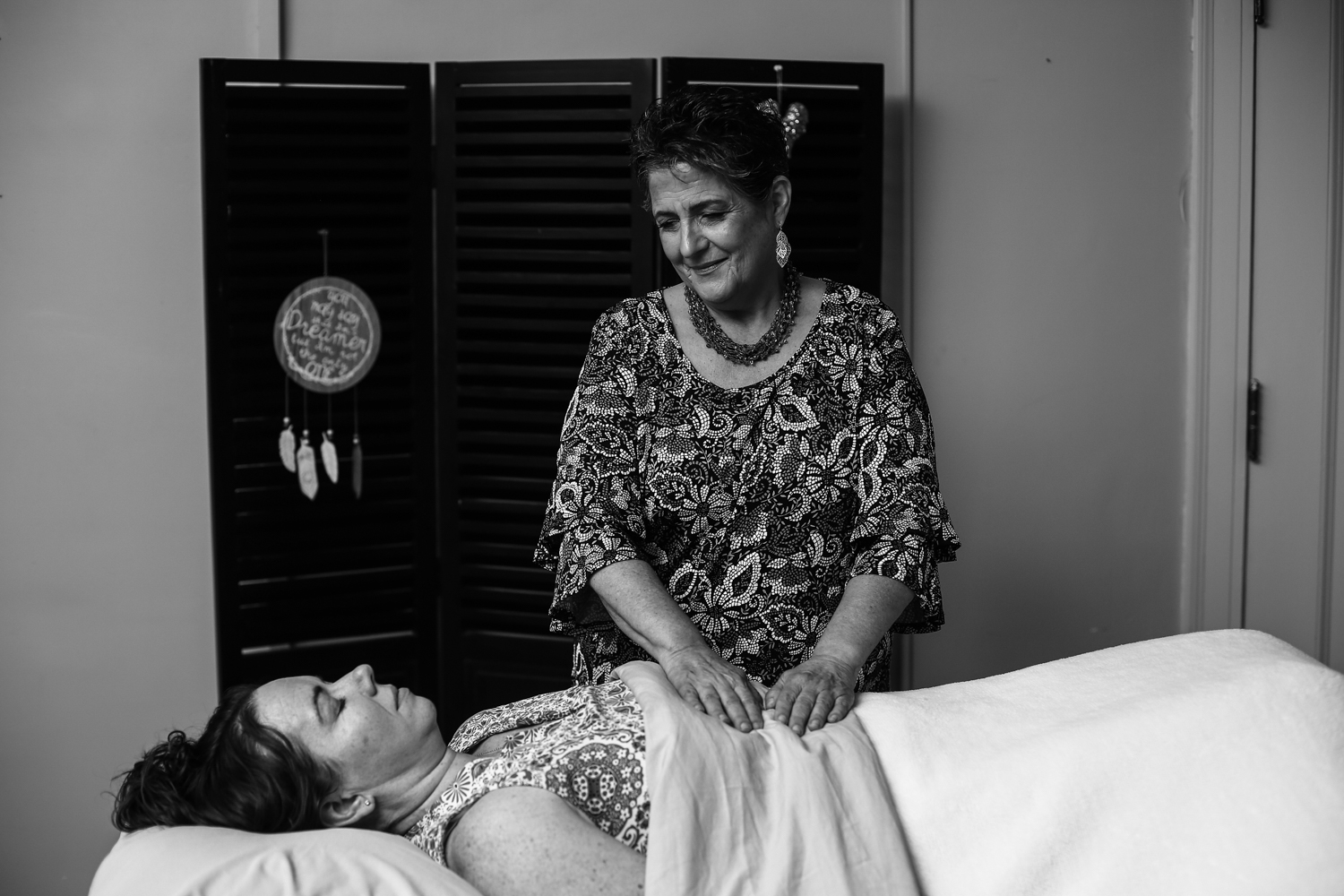 Woman performing Reiki session on woman lying on a table 